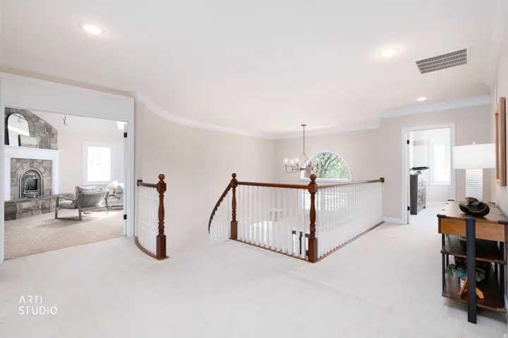Hall with suspended lighting, carpet, ornamental molding, and an upstairs landing