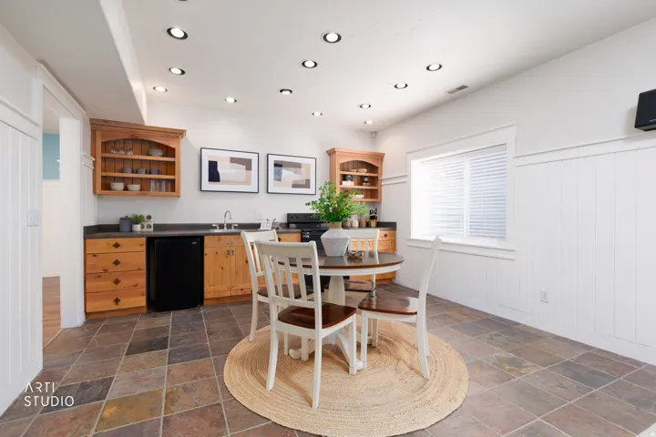 Dining room featuring wainscoting, stone tile flooring, recessed lighting, and wet bar