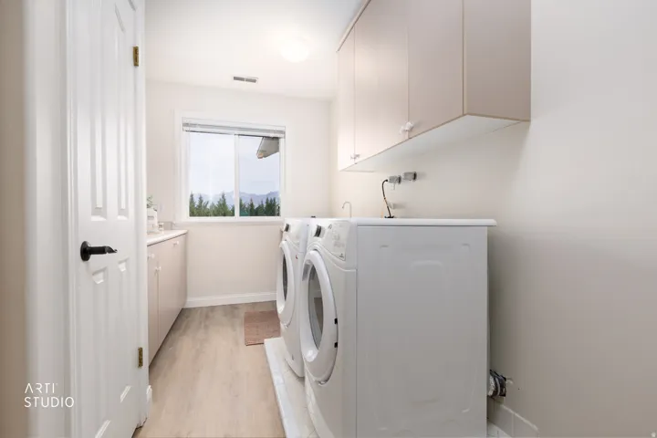 Laundry room with cabinet space, light wood-type flooring, and washing machine and dryer