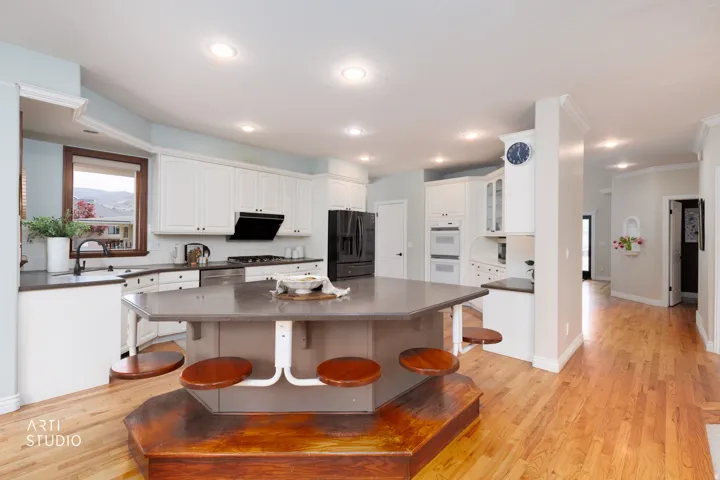 Kitchen with a kitchen breakfast bar, dark countertops, stainless steel appliances, white cabinets, and ornamental molding