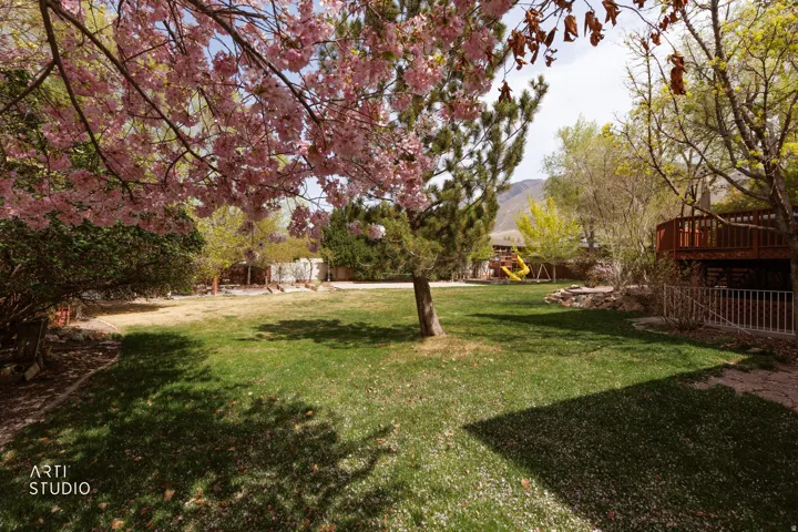 View of grassy yard with a deck with mountain view and a playground