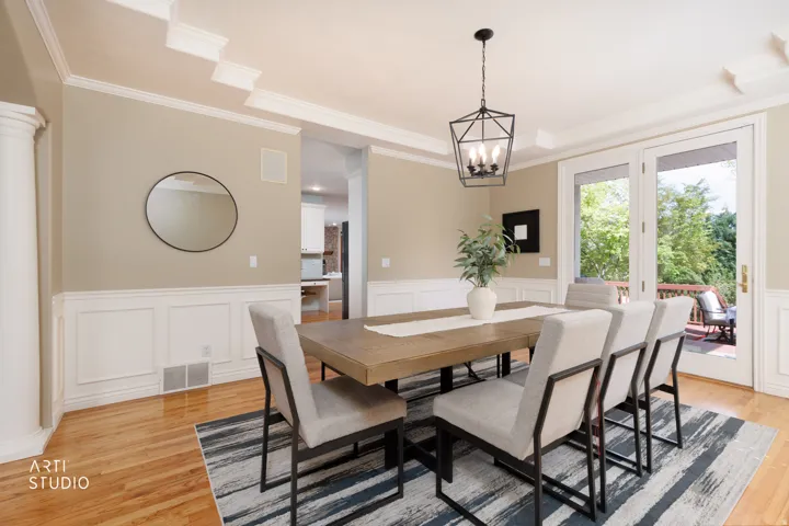 Dining room with a wainscoted wall, suspended lighting, a decorative wall, light wood-style floors, and ornamental molding