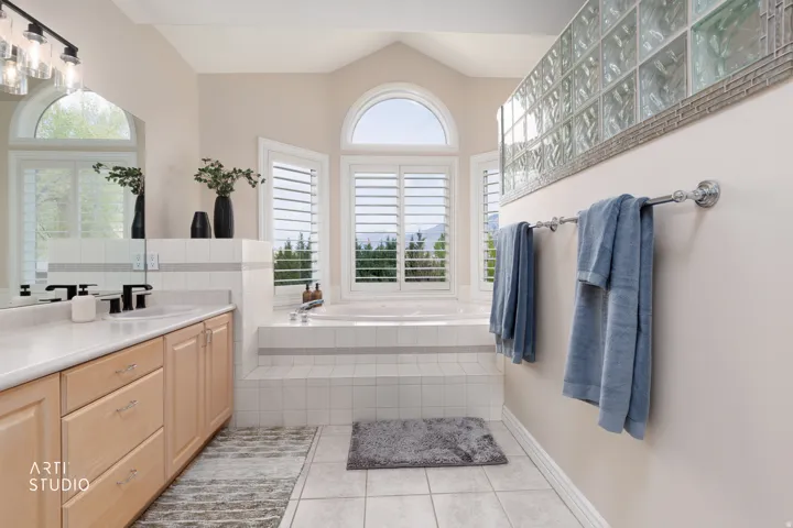 Full bathroom featuring vanity, light tile patterned flooring, a garden tub, lofted ceiling, and healthy amount of natural light