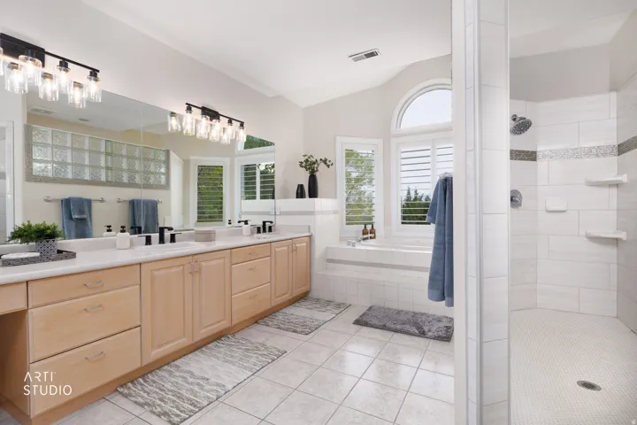 Full bath with a shower stall, double vanity, a bath, vaulted ceiling, and light tile patterned flooring