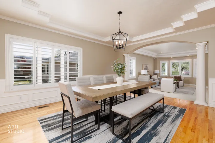 Dining space featuring a wainscoted wall, a decorative wall, arched walkways, a tray ceiling, and light wood-style floors
