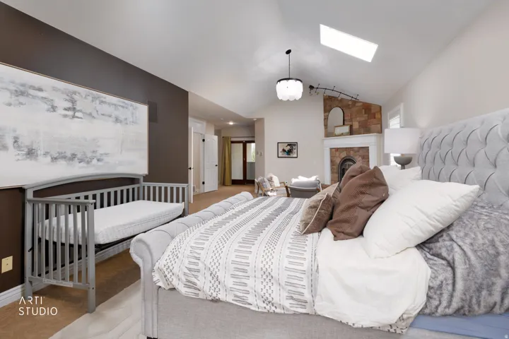 Bedroom featuring vaulted ceiling, a large fireplace, a skylight, and light carpet