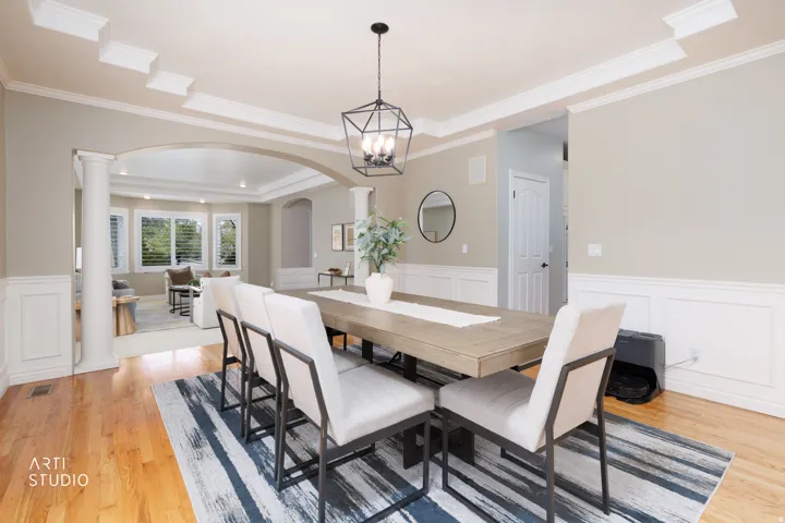 Dining area with a wainscoted wall, a decorative wall, light wood-style flooring, a raised ceiling, and a chandelier