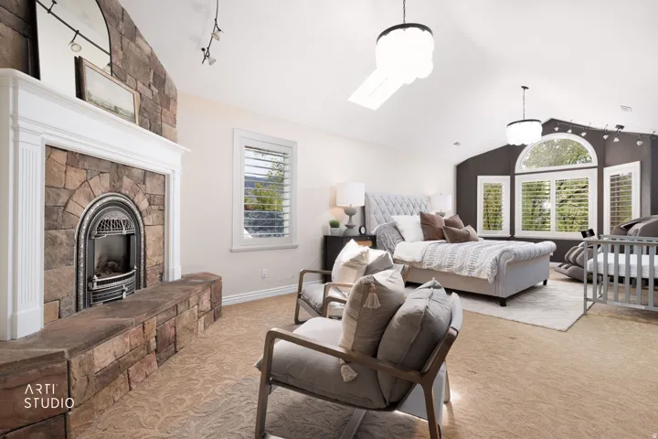 Bedroom with light carpet, a fireplace with raised hearth, track lighting, and a skylight