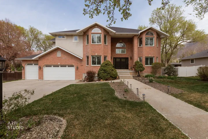 View of front of house featuring an attached garage, driveway, and brick siding