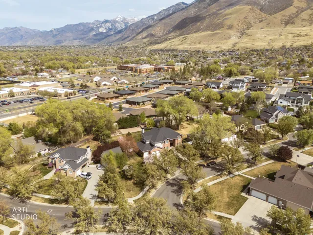 Aerial view of property and surrounding area featuring nearby suburban area and a mountain backdrop