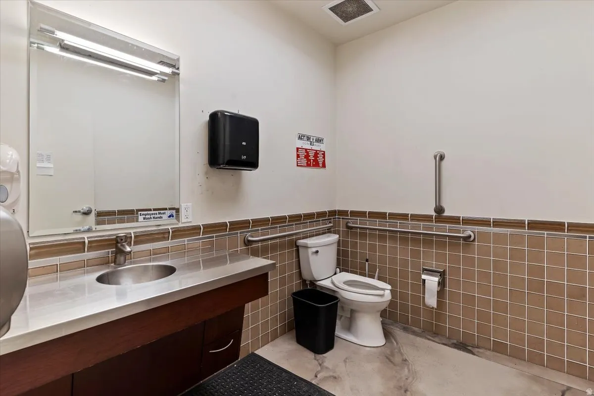 Bathroom 1 featuring vanity, tile walls, and wainscoting