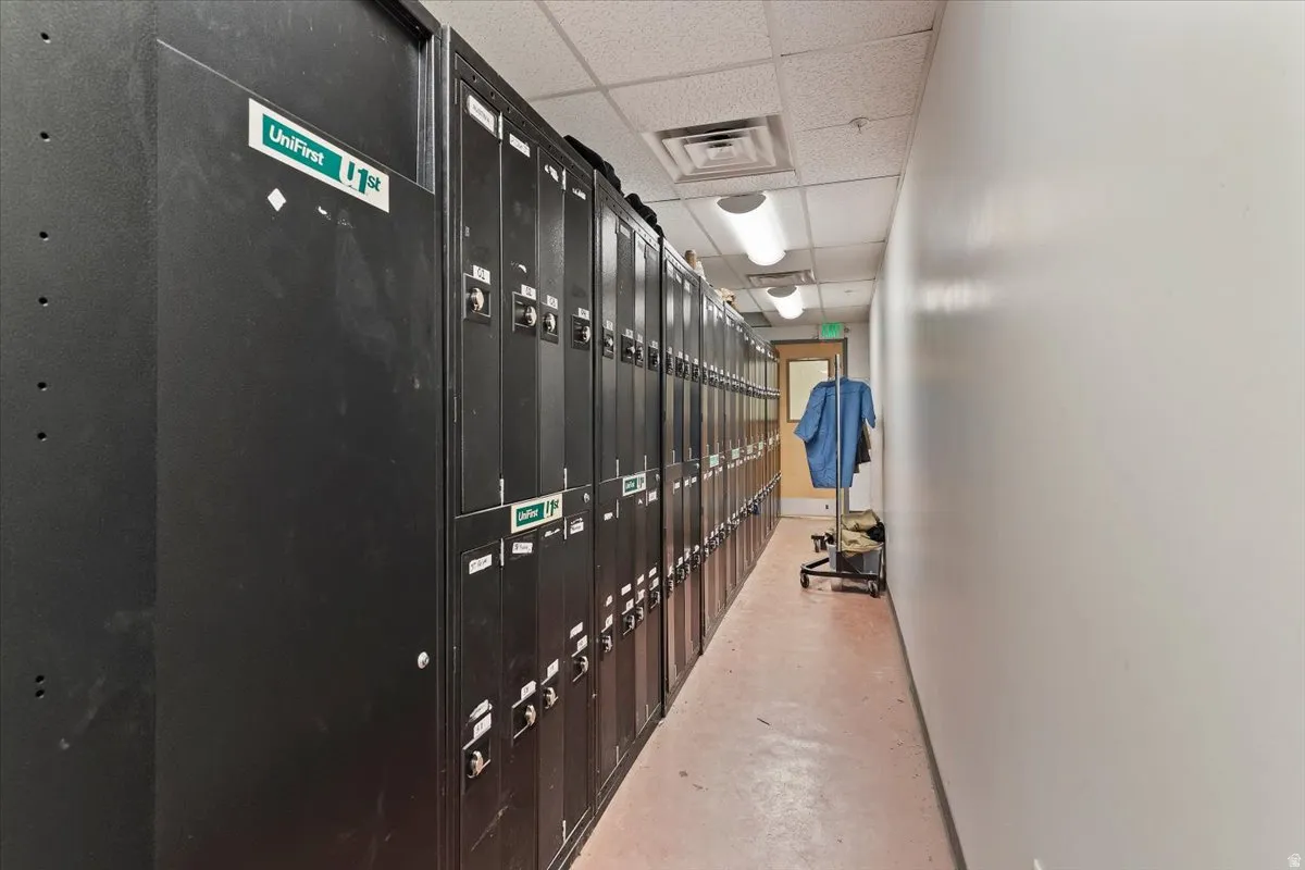 Hall with a paneled ceiling, finished concrete flooring, and a package area