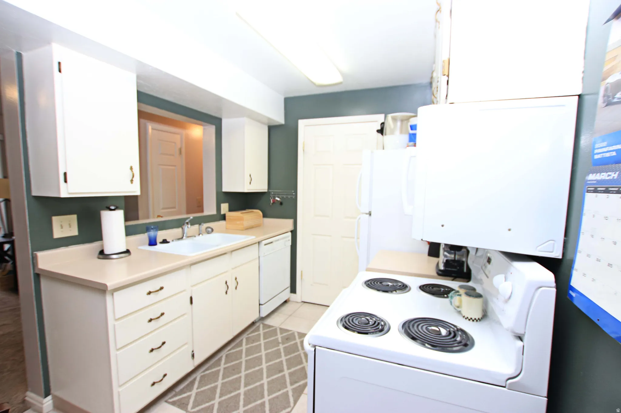 Kitchen featuring white appliances, white cabinetry, and light countertops