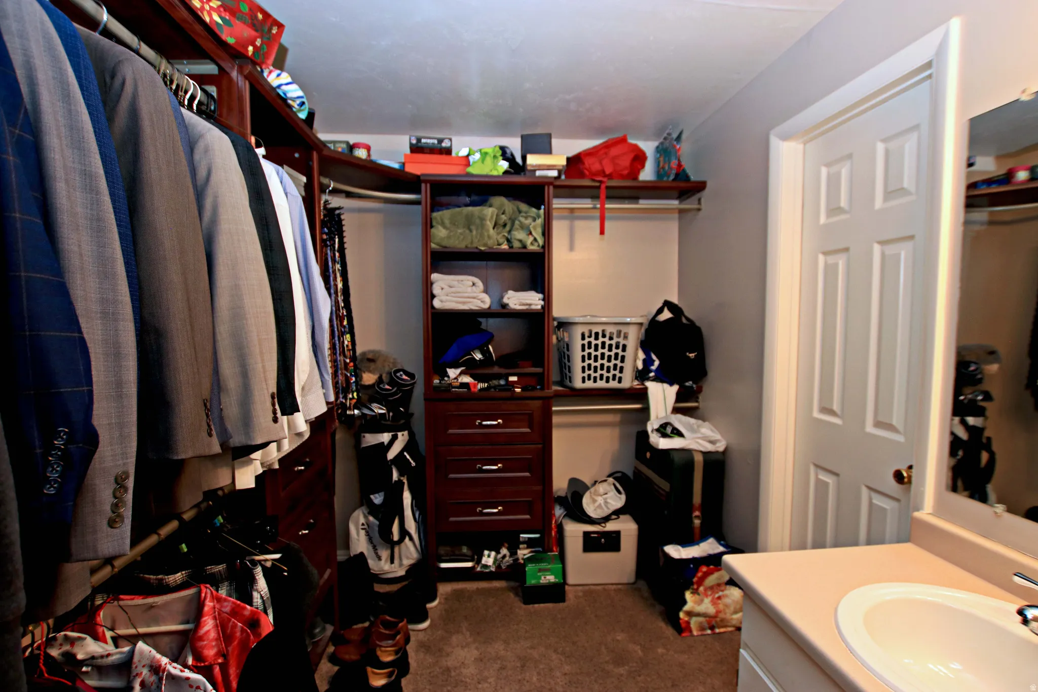 Walk in closet with dark colored carpet and a sink