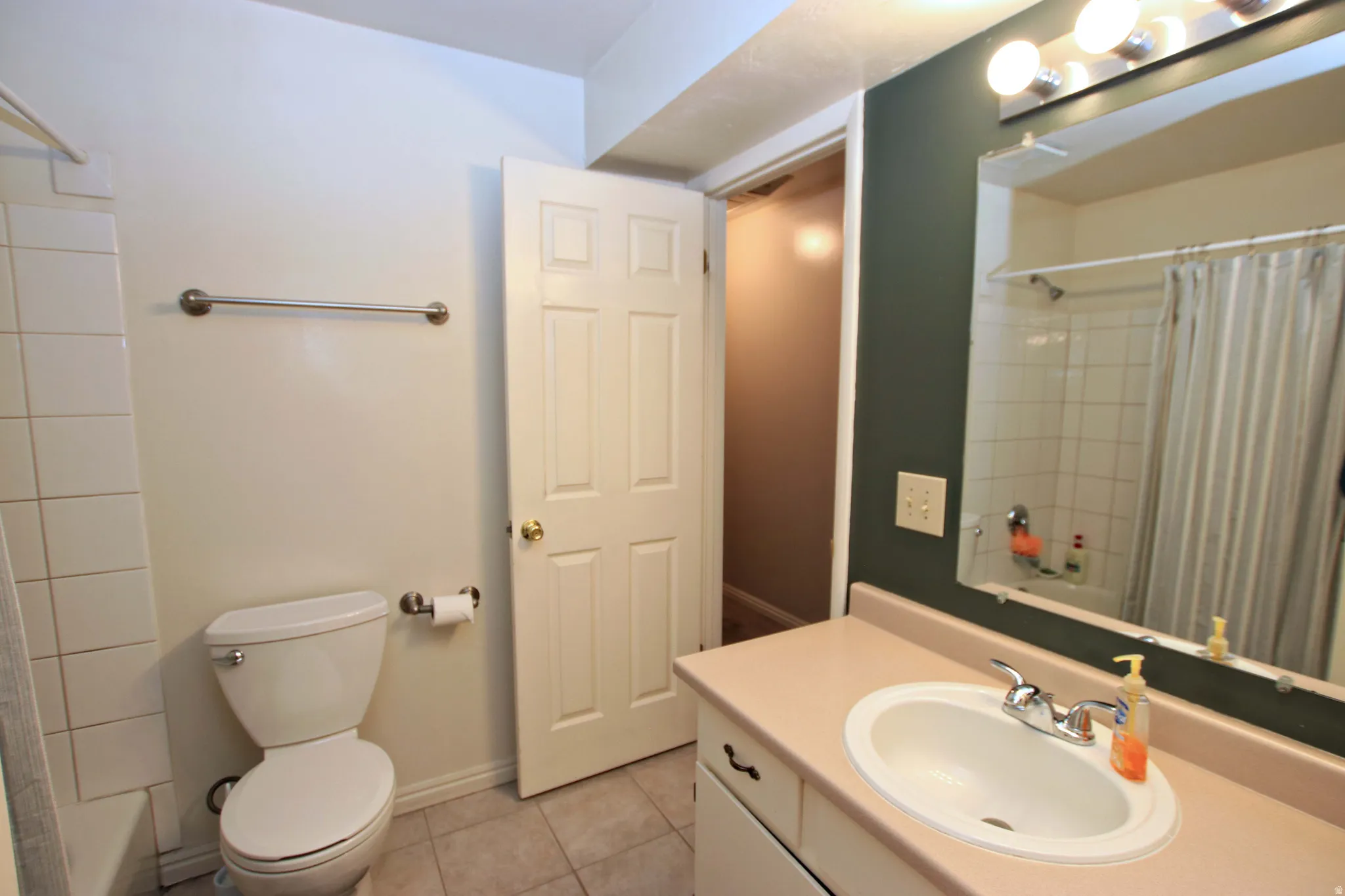 Bathroom with shower / bathtub combination with curtain, vanity, and light tile patterned flooring
