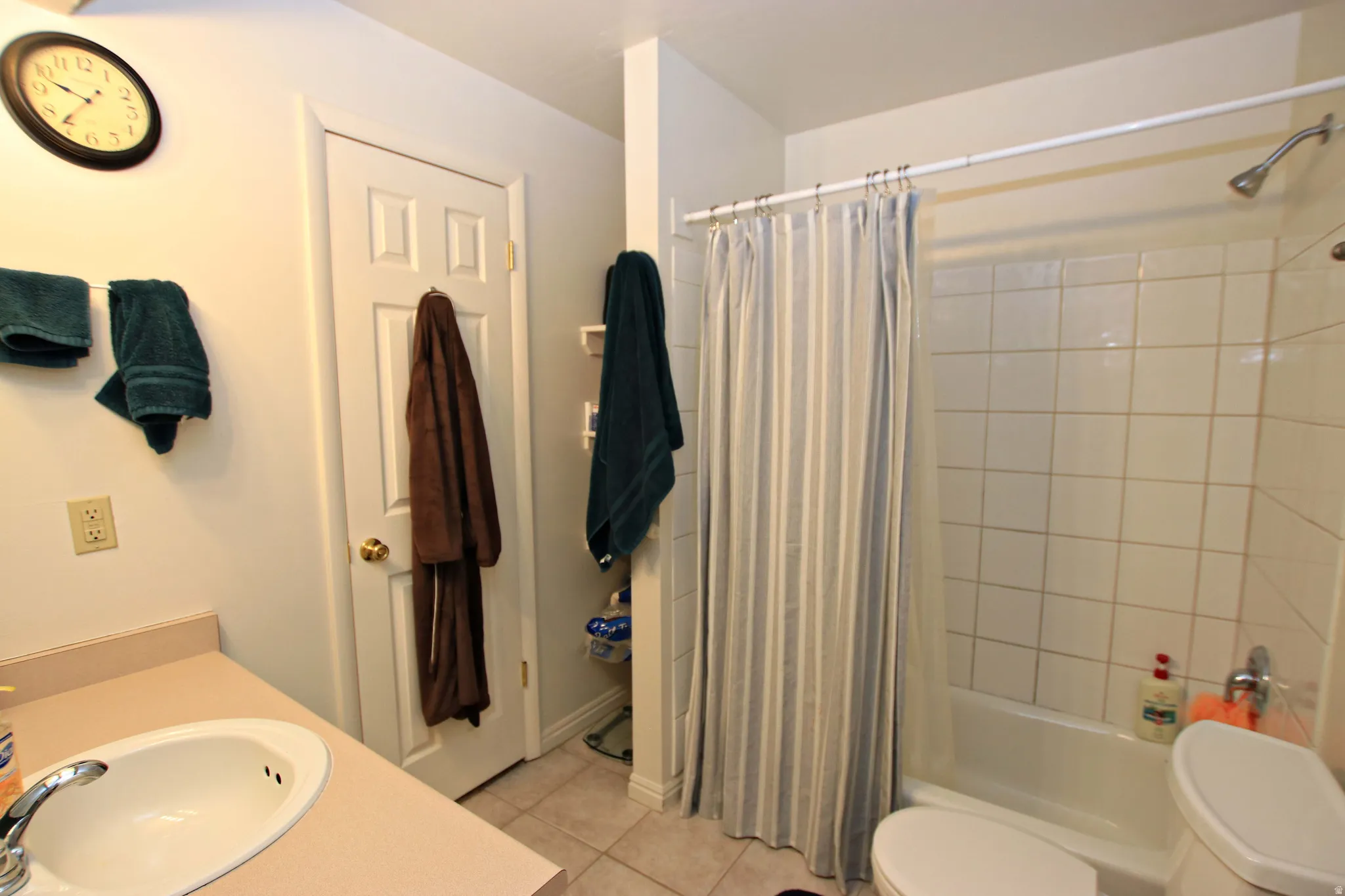 Bathroom featuring vanity, shower / bath combination with curtain, and light tile patterned flooring