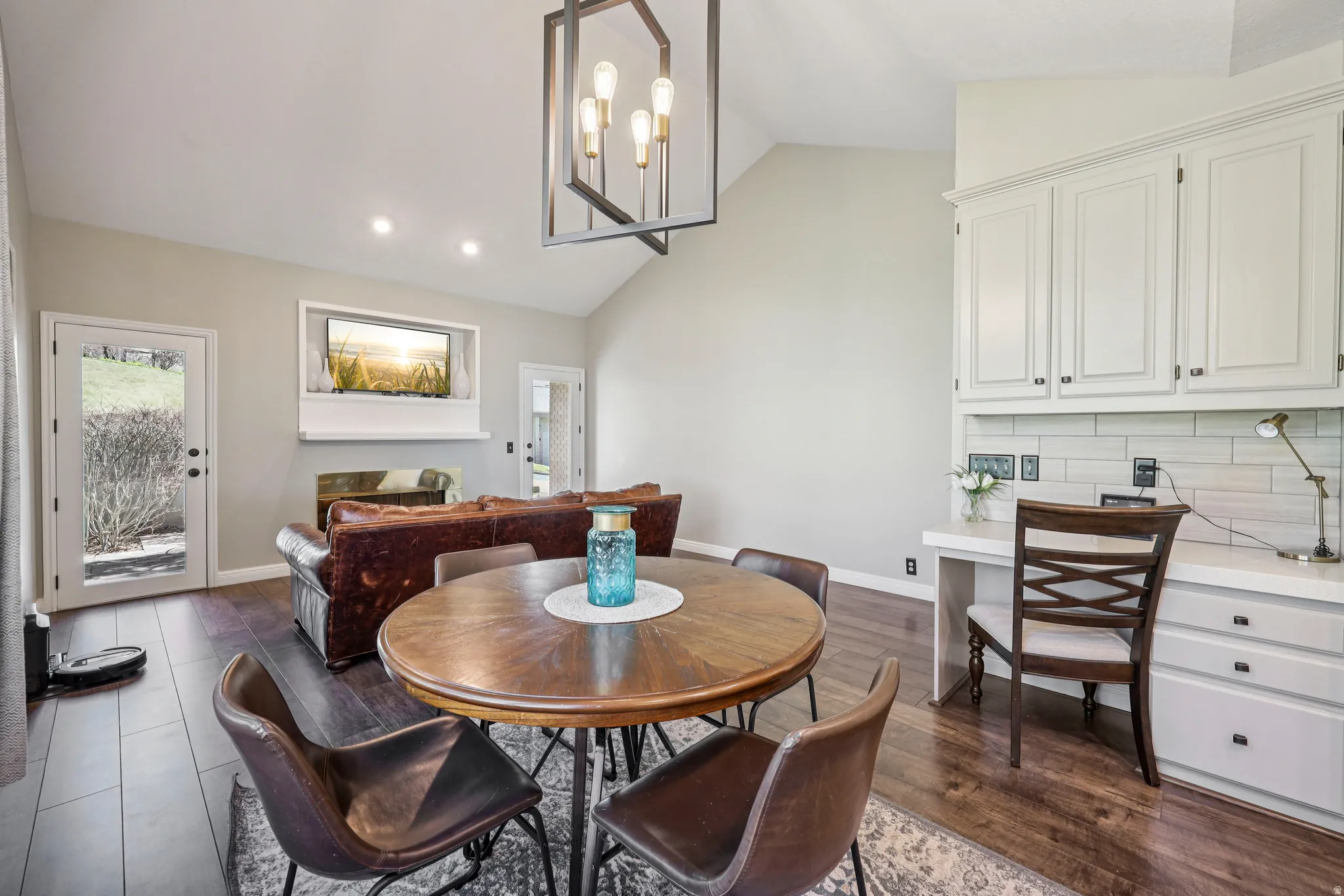 Dining room with lofted ceiling, a chandelier, dark wood-style flooring, and a fireplace