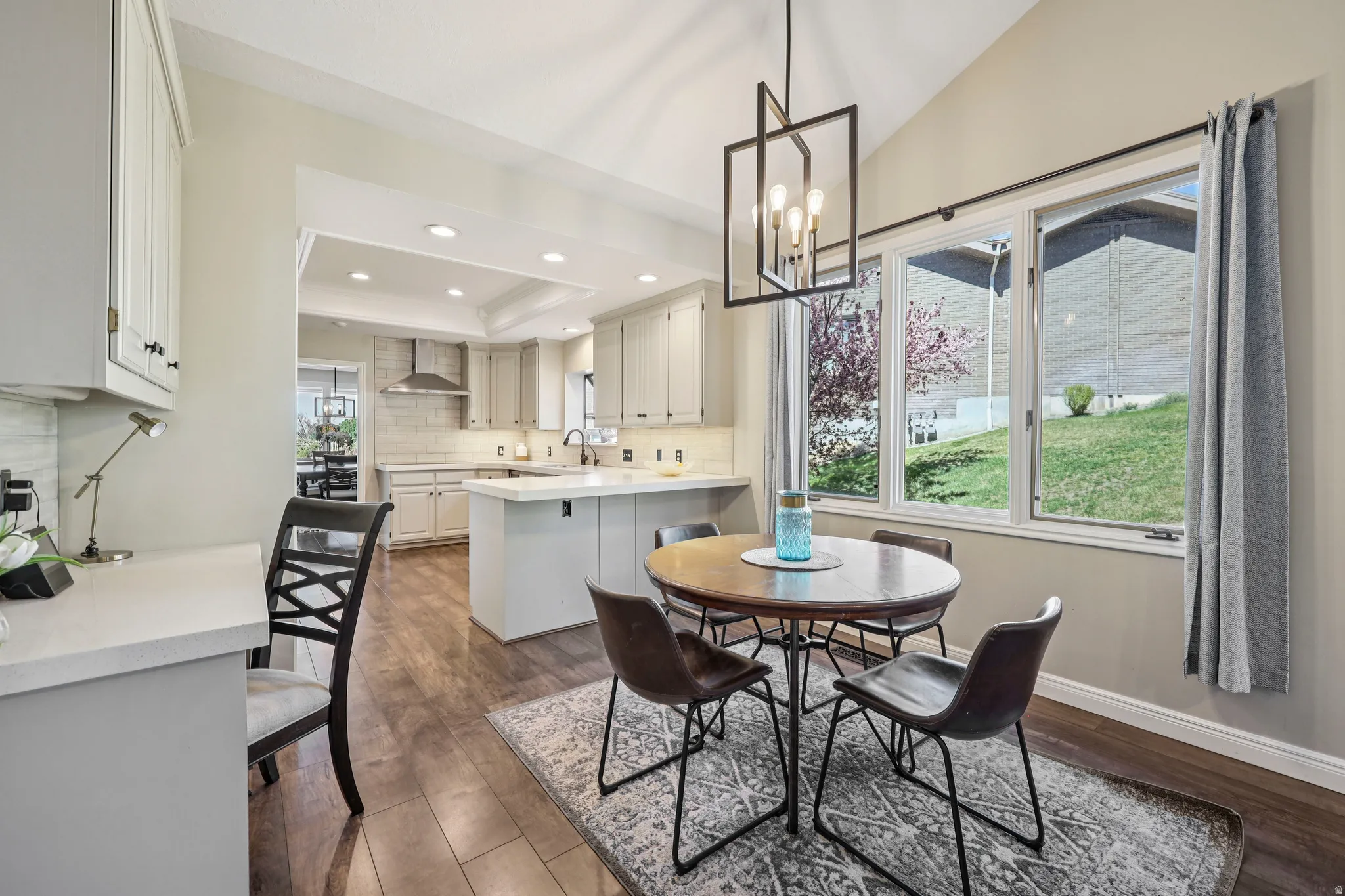Dining area featuring dark wood finished floors, suspended lighting, and a tray ceiling
