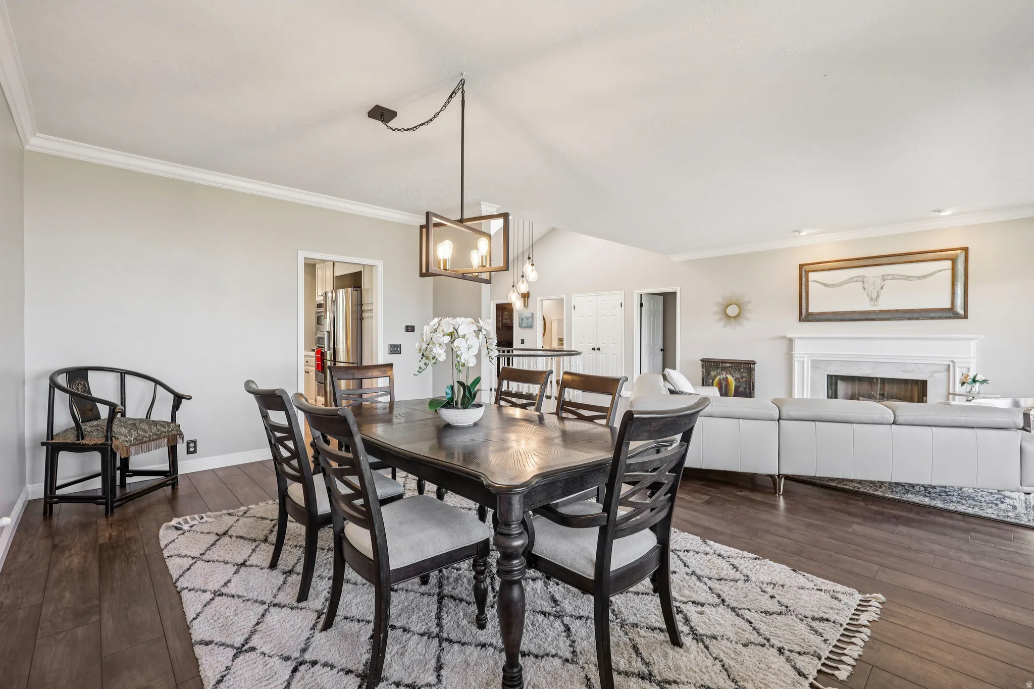 Dining space featuring crown molding, a fireplace, dark wood-type flooring, hanging lights, and lofted ceiling
