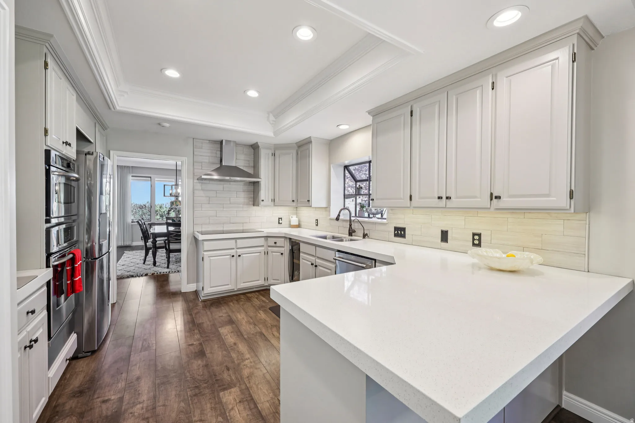 Kitchen featuring a peninsula, dark wood-type flooring, decorative backsplash, recessed lighting, and stainless steel appliances