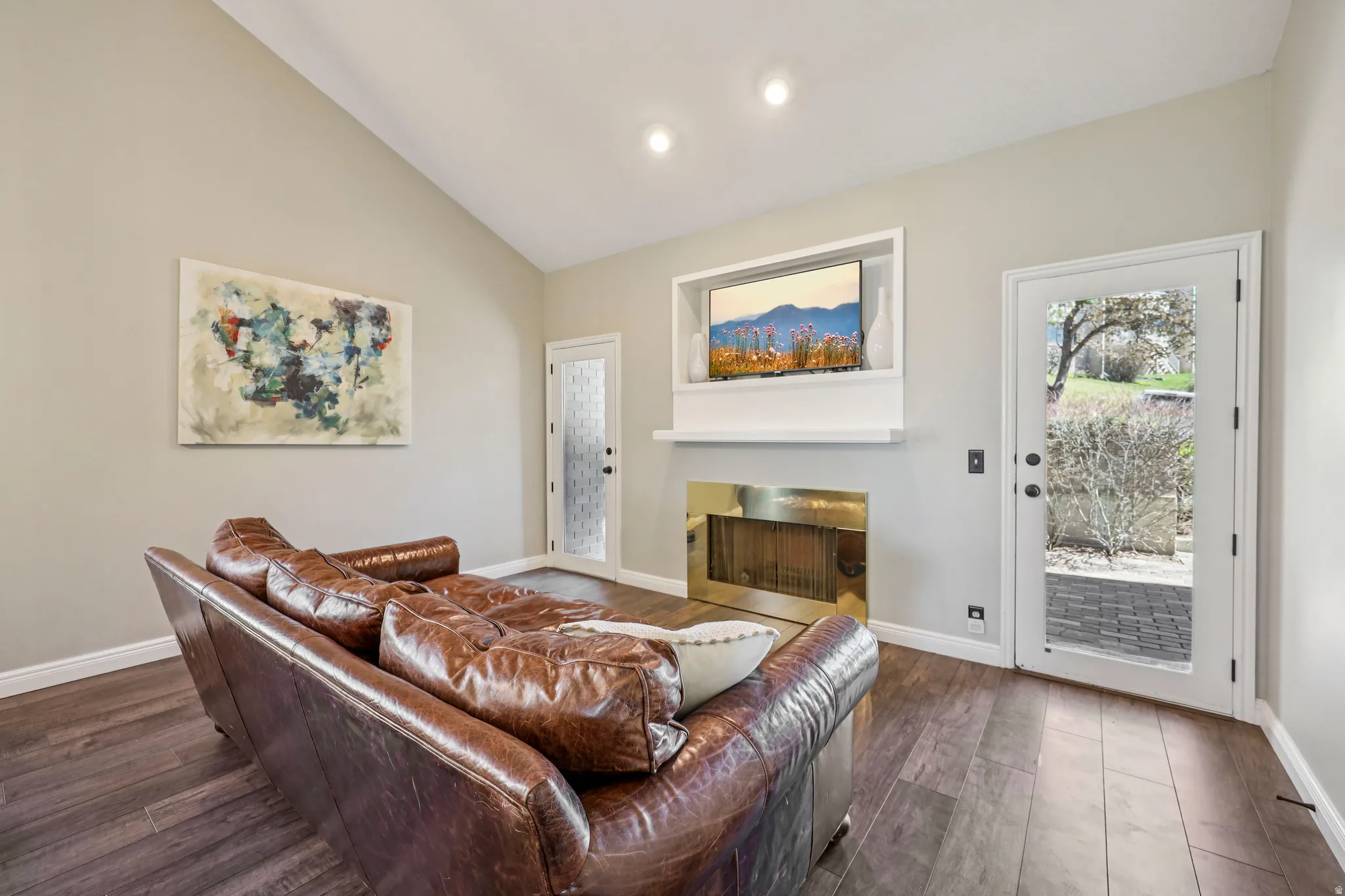 Living area featuring dark wood-style flooring, a fireplace, vaulted ceiling, and recessed lighting