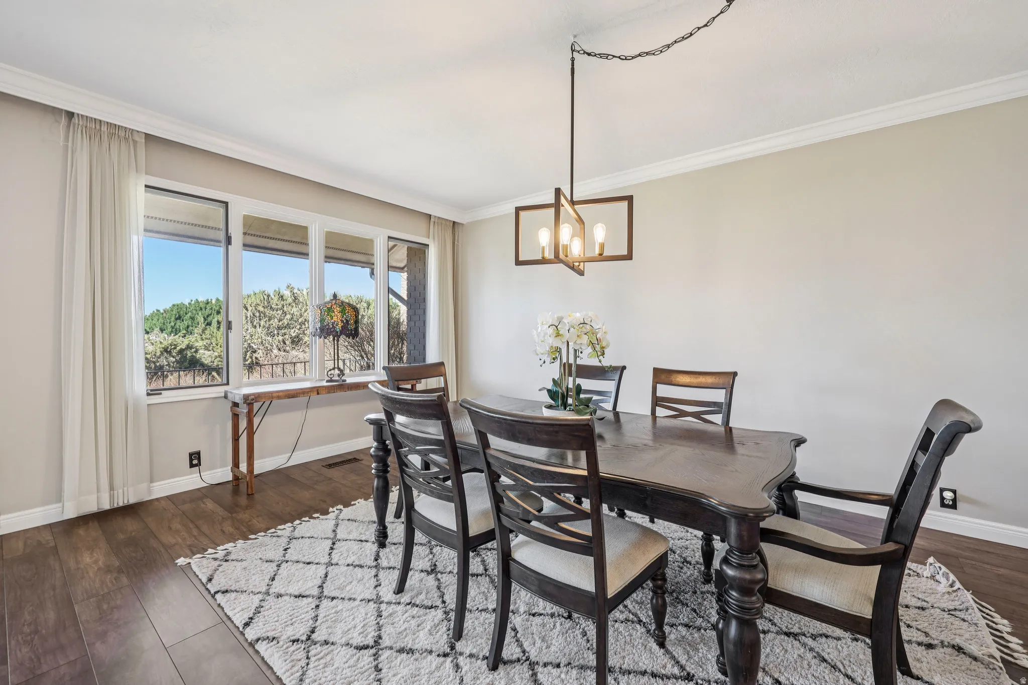 Dining area featuring dark wood-style floors, ornamental molding, and hanging lights