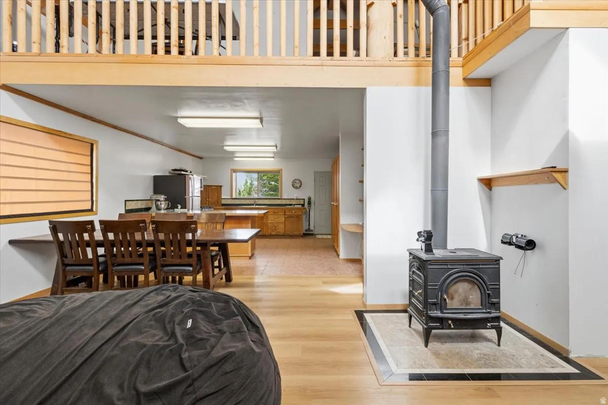 Living area with light wood-type flooring, a wood stove, ornamental molding, and a high ceiling