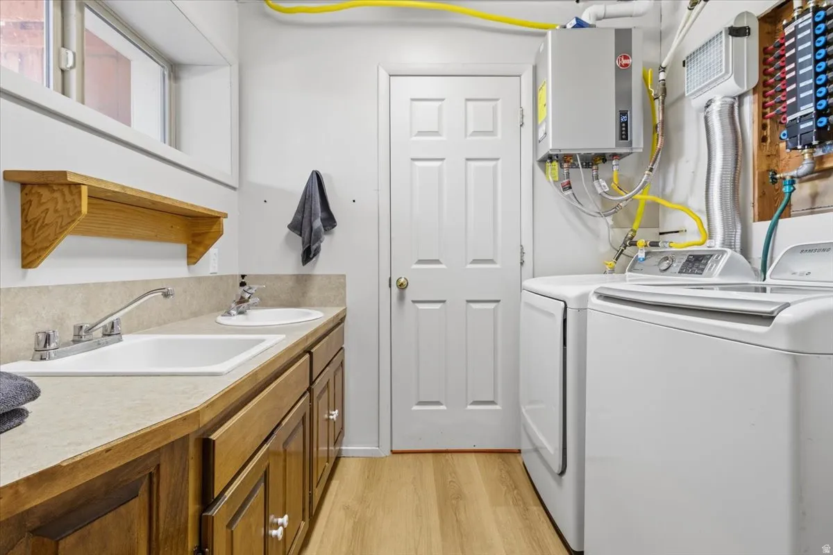 Laundry area featuring washing machine and dryer, light wood-type flooring, and water heater