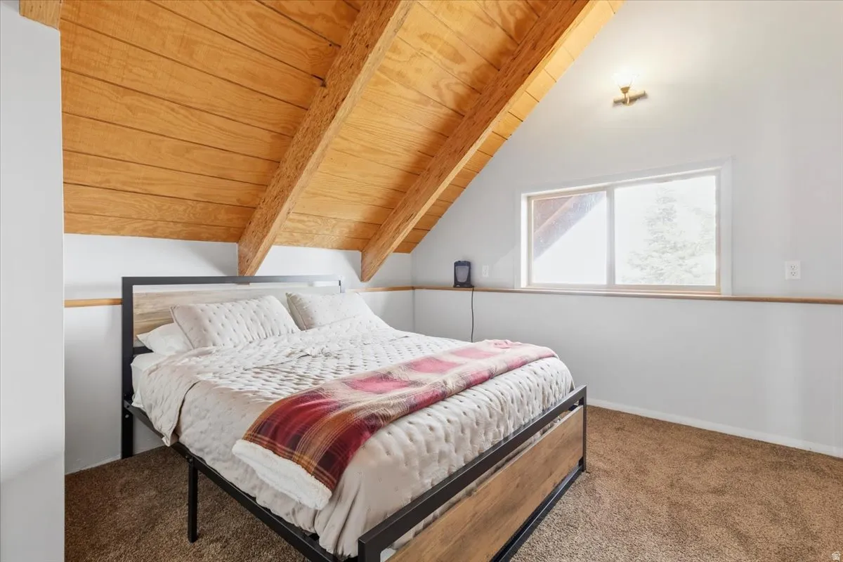 Bedroom with wood ceiling, carpet floors, and lofted ceiling with beams