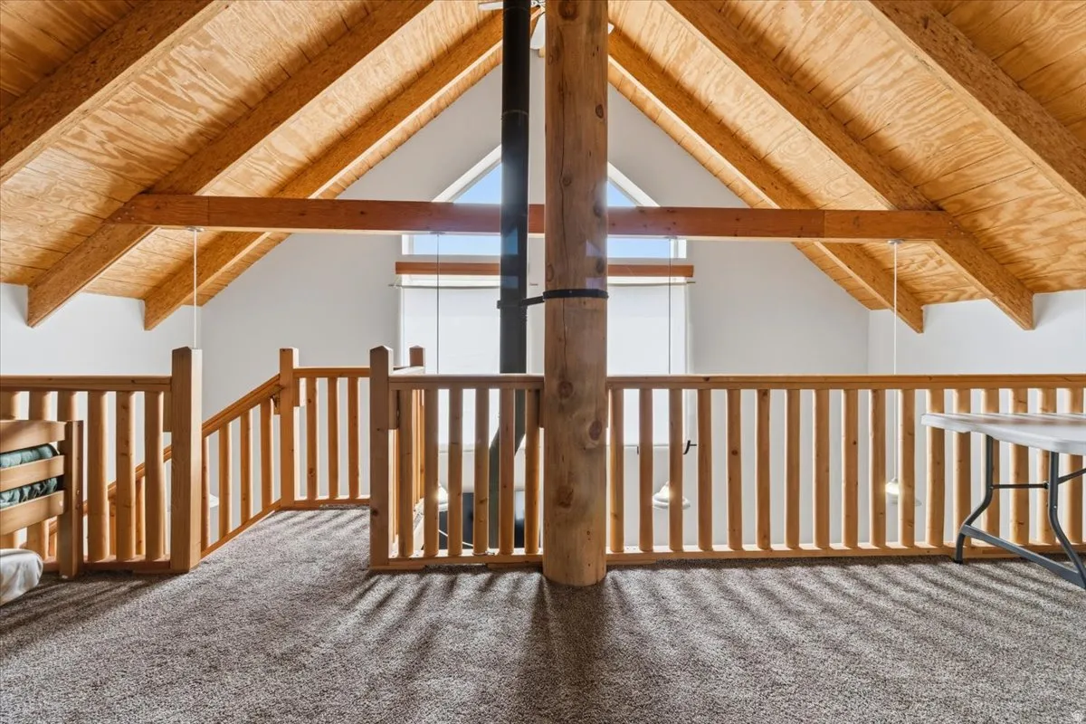 Interior space featuring carpet floors and a wood ceiling with exposed beams