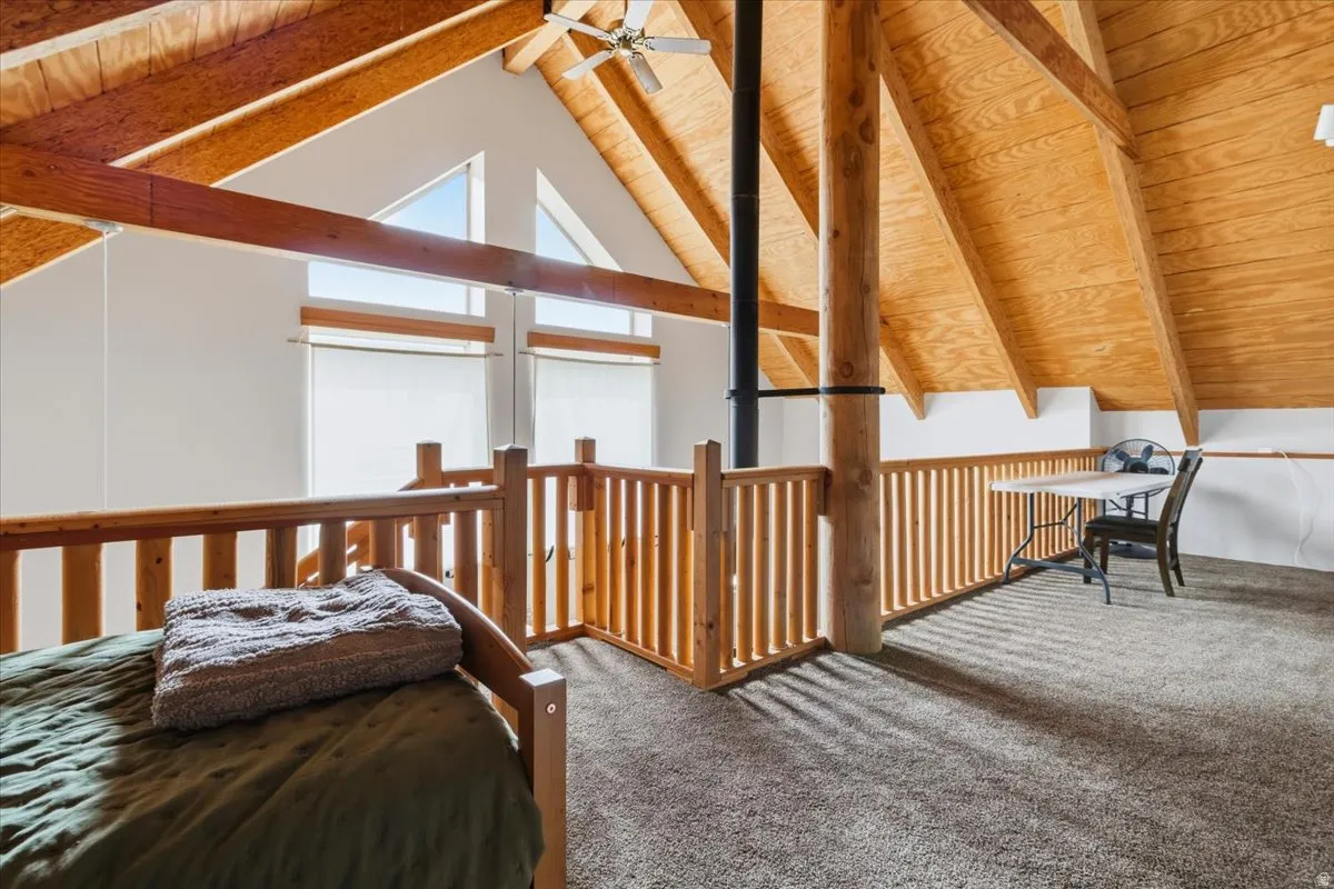 Bedroom featuring carpet floors and a wood ceiling with exposed beams