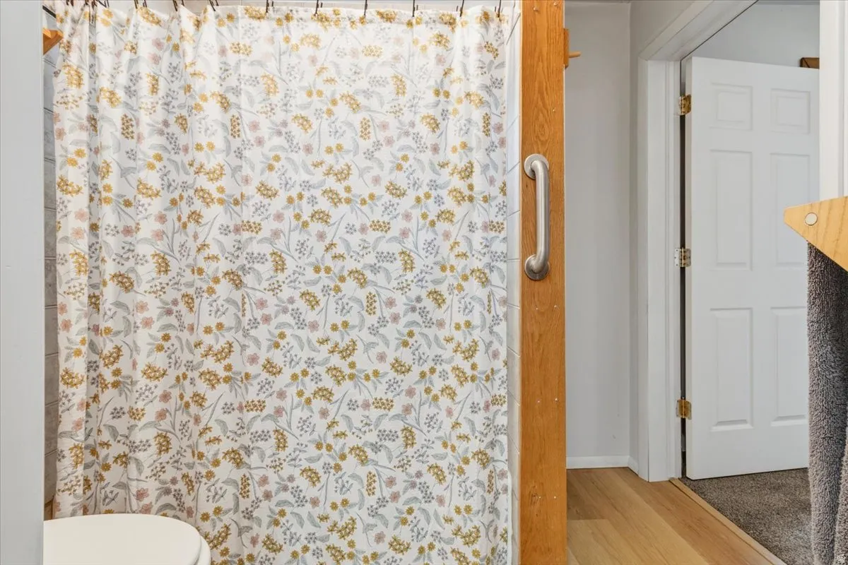 Bathroom with curtained shower and light wood-style flooring