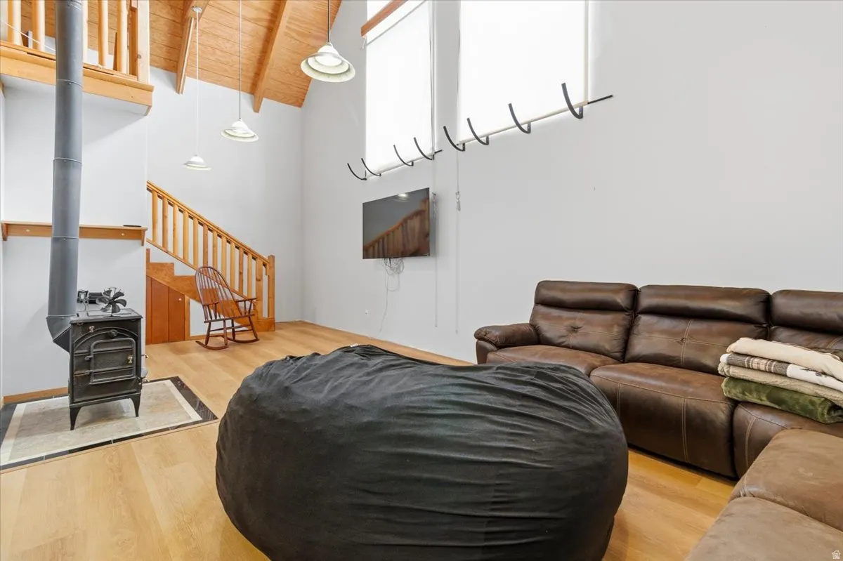 Living area featuring a wood stove, light wood-style floors, and a high wood beamed ceiling