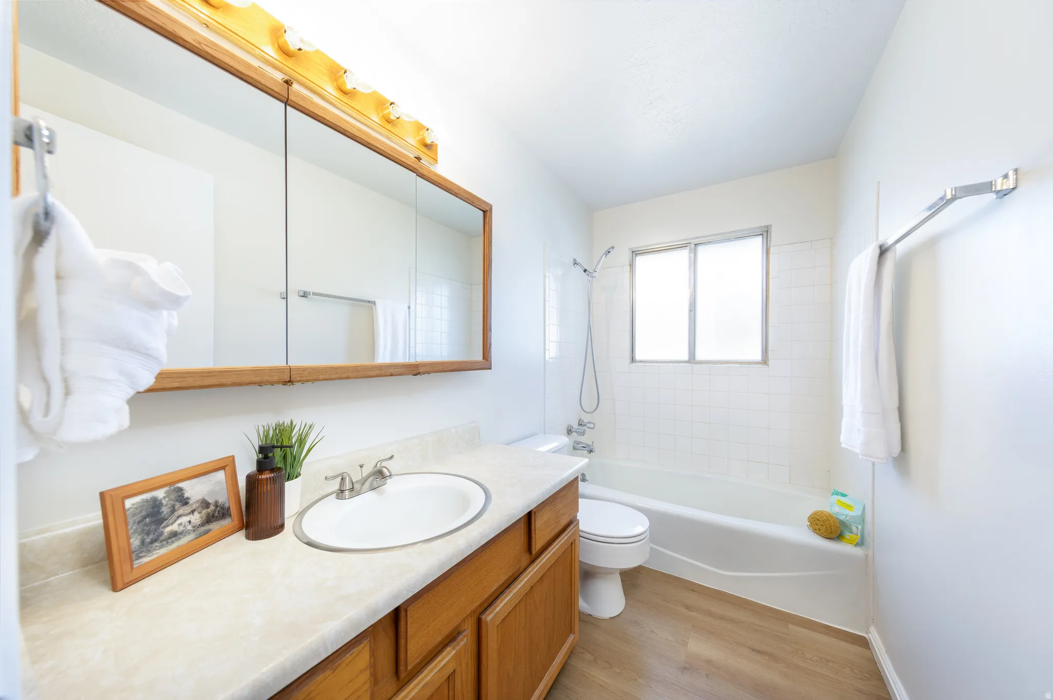 Full bathroom featuring vanity, shower / bath combination, and light wood-type flooring