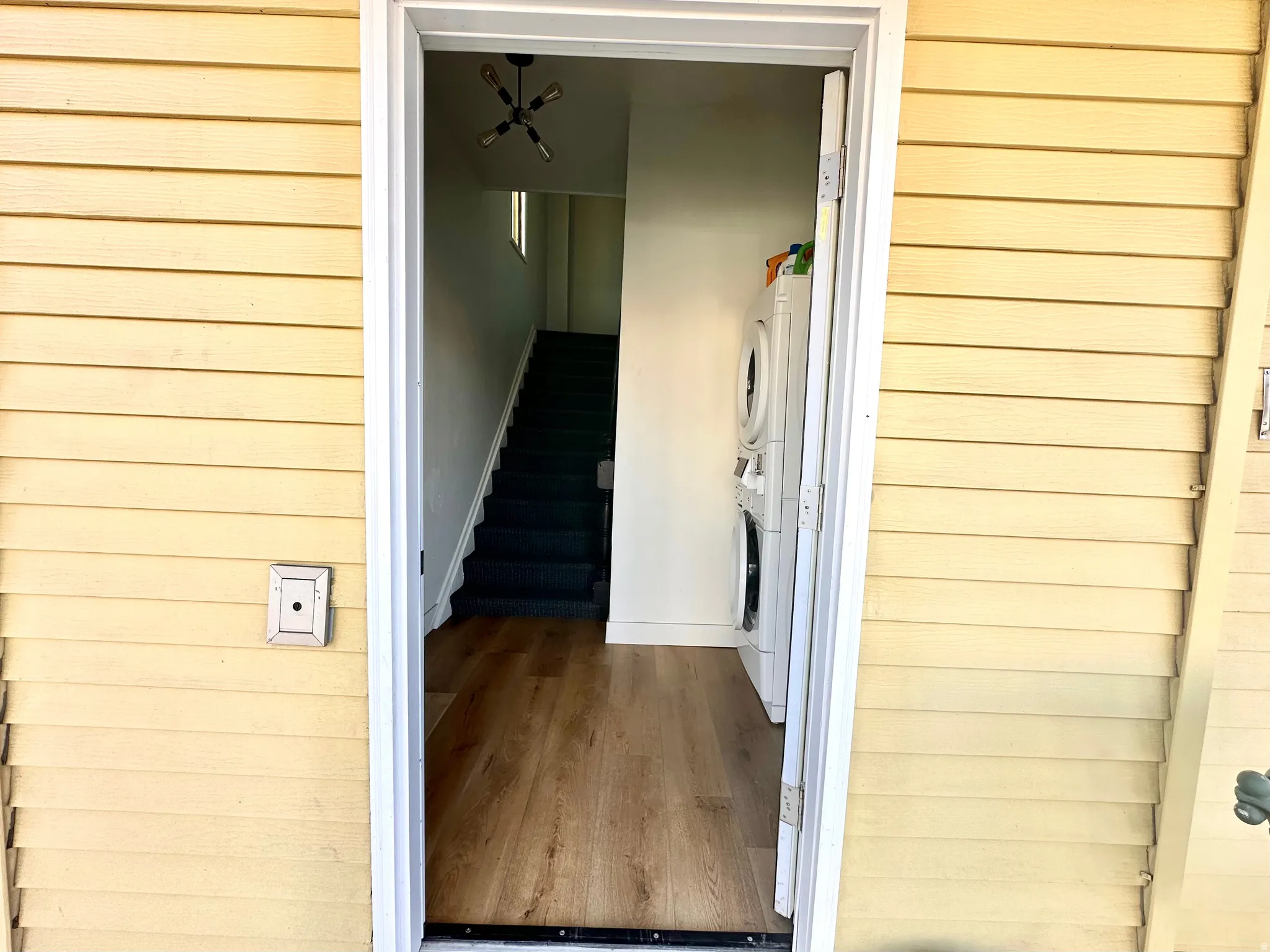 Doorway to property featuring stacked washer / dryer
