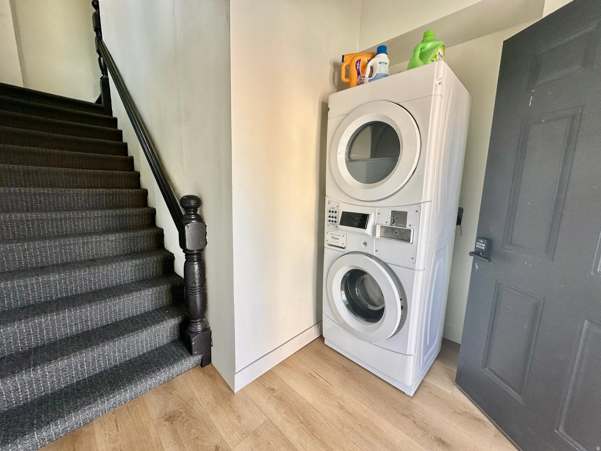 Laundry area featuring stacked washer / drying machine and light wood-type flooring