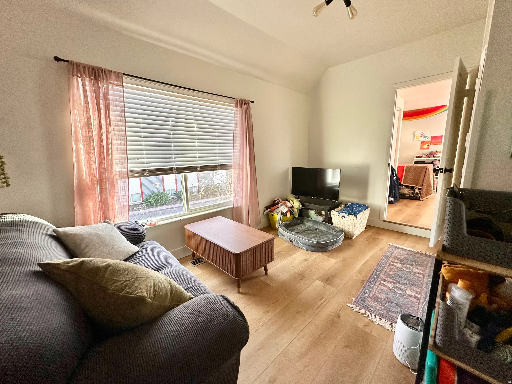 Living room with light wood-style flooring and vaulted ceiling