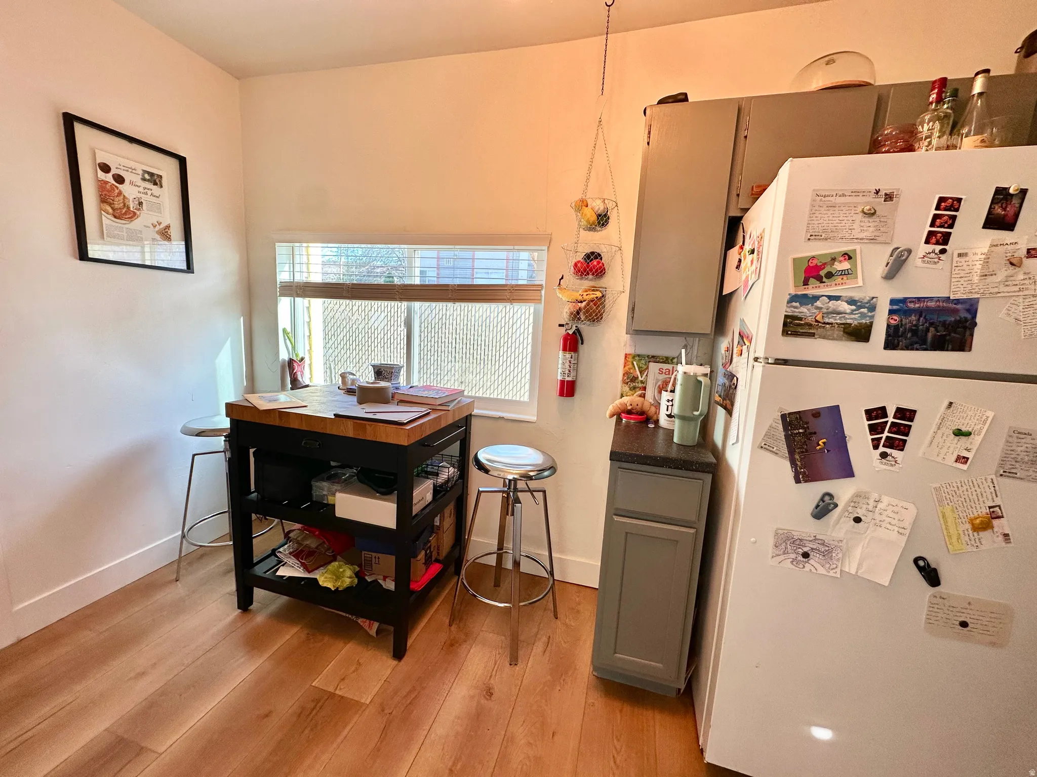 Kitchen with freestanding refrigerator, dark countertops, gray cabinets, and light wood-type flooring
