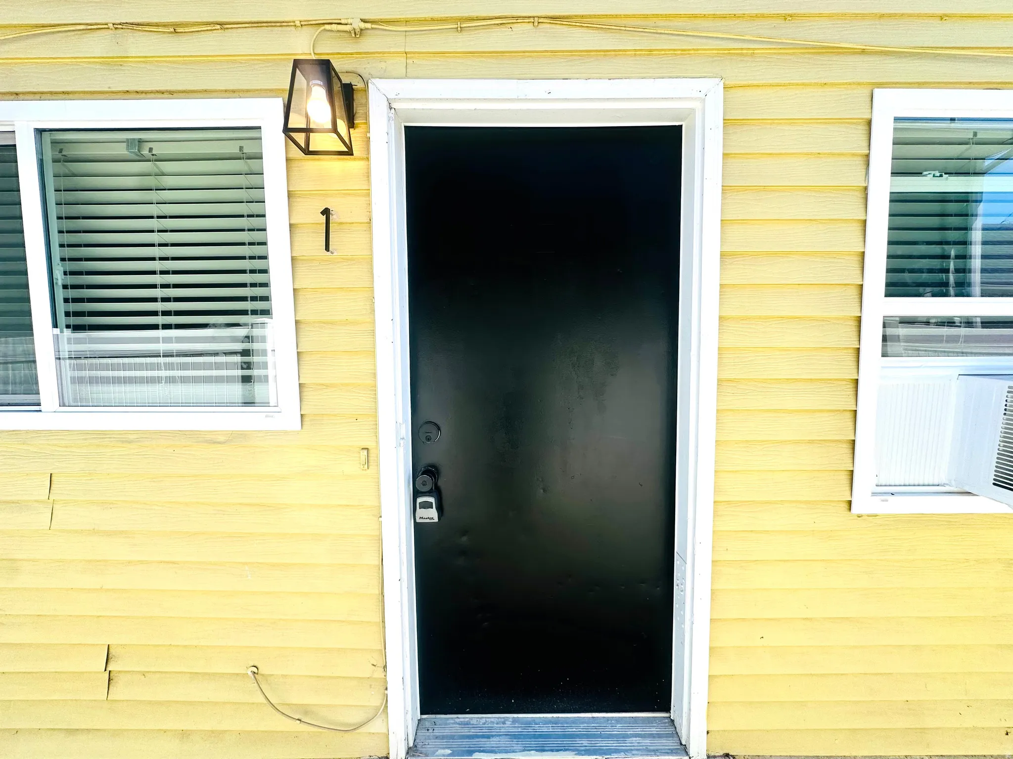 Entry door with a dark finish, flanked by windows with white blinds