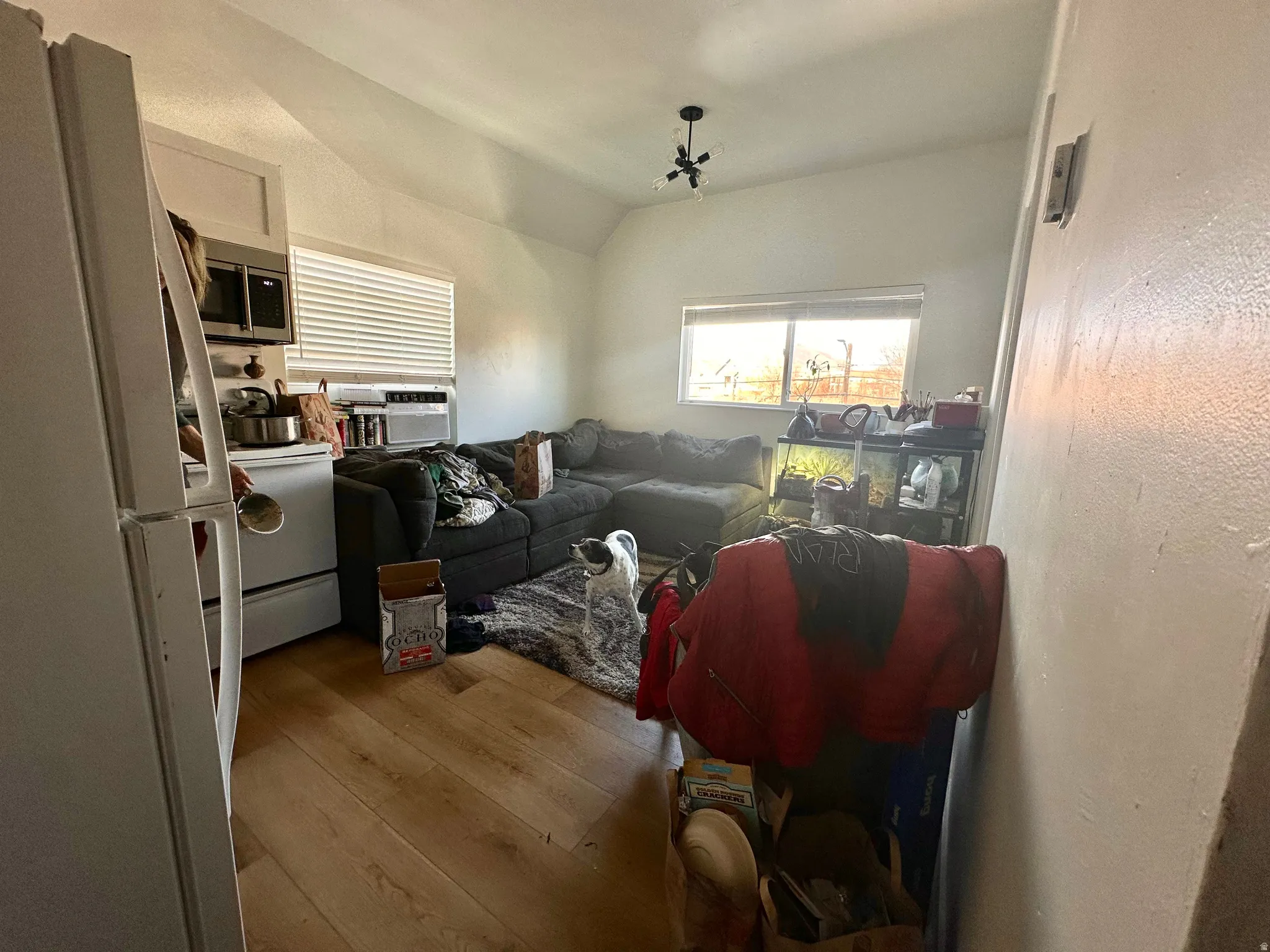 Living area with light wood-type flooring, vaulted ceiling, and cooling unit
