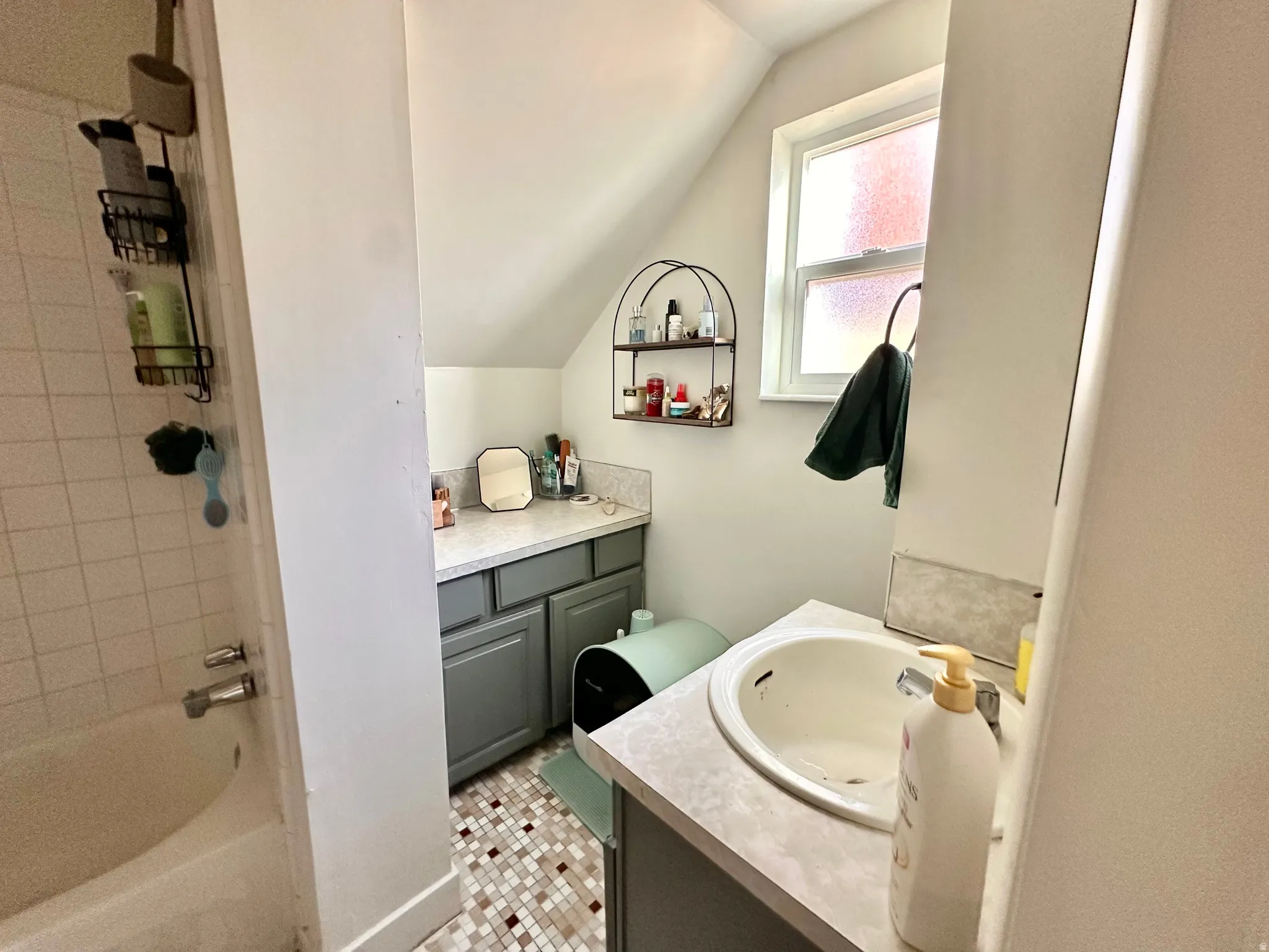 Full bath featuring vanity, bathing tub / shower combination, lofted ceiling, and light tile patterned flooring