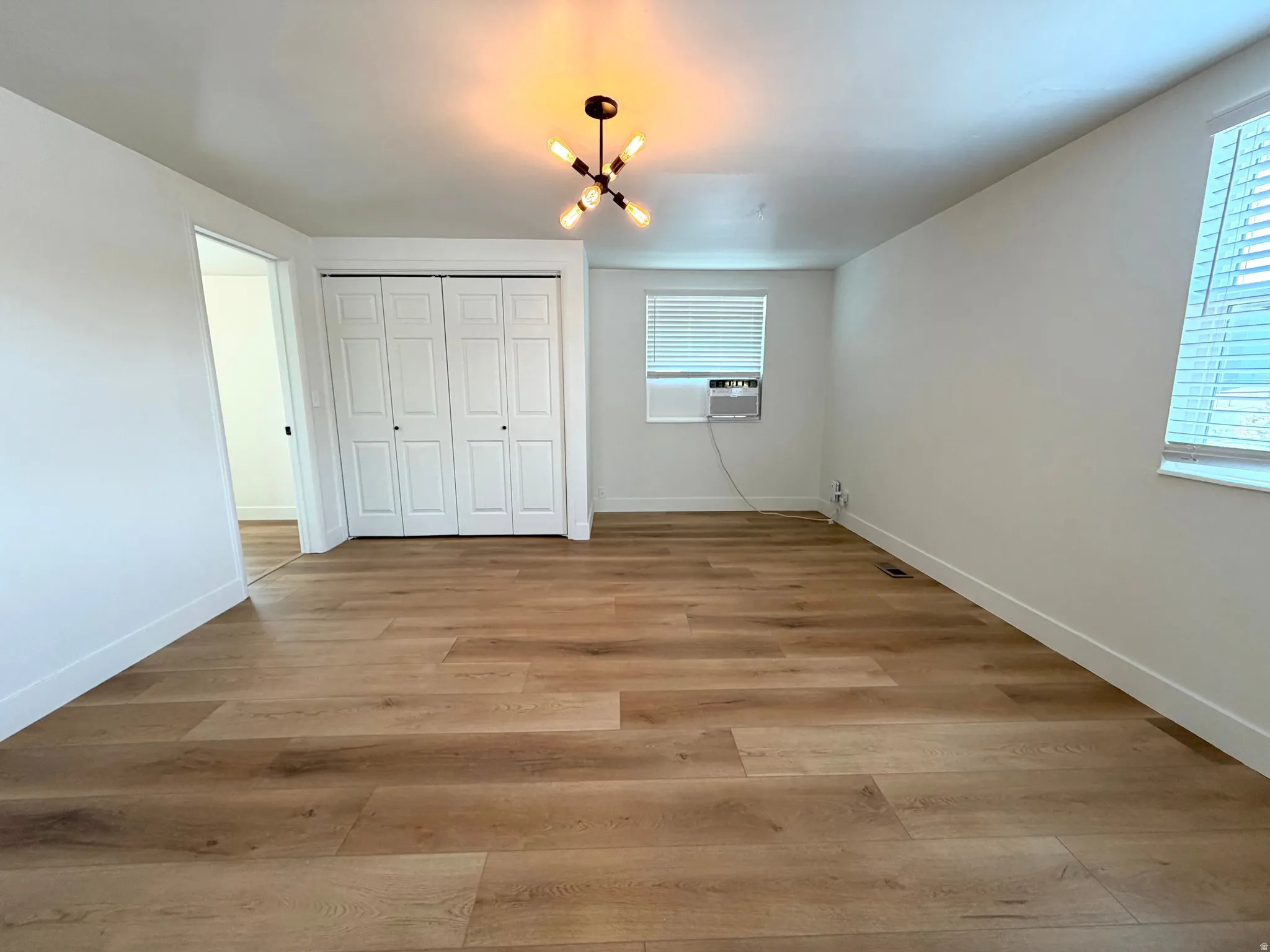 Wood-finish flooring throughout, white bi-fold closet doors, and a modern ceiling light fixture