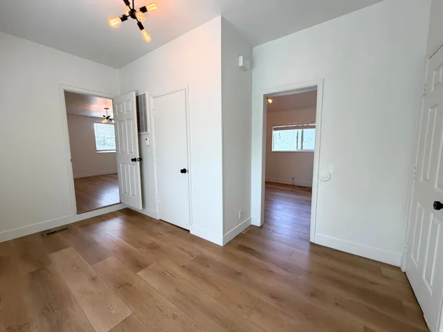 Wood-finish flooring throughout, bright white walls, and contemporary light fixtures