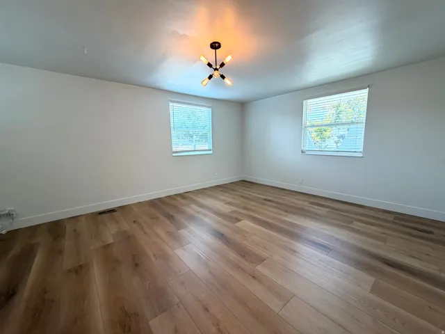 Wood-finish flooring, white walls, two windows with blinds, and a contemporary ceiling fixture
