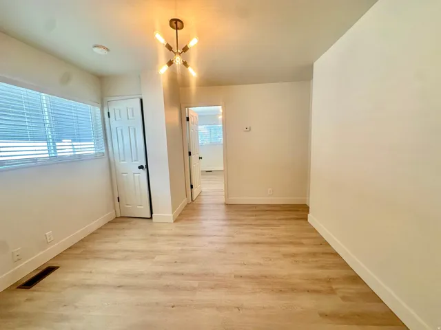 Bright interior space featuring wood-finish flooring, white baseboards, and a contemporary ceiling fixture