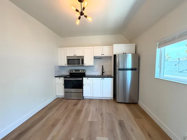Well-appointed kitchen featuring stainless steel appliances, white cabinetry, dark countertops, and a white tile backsplash
