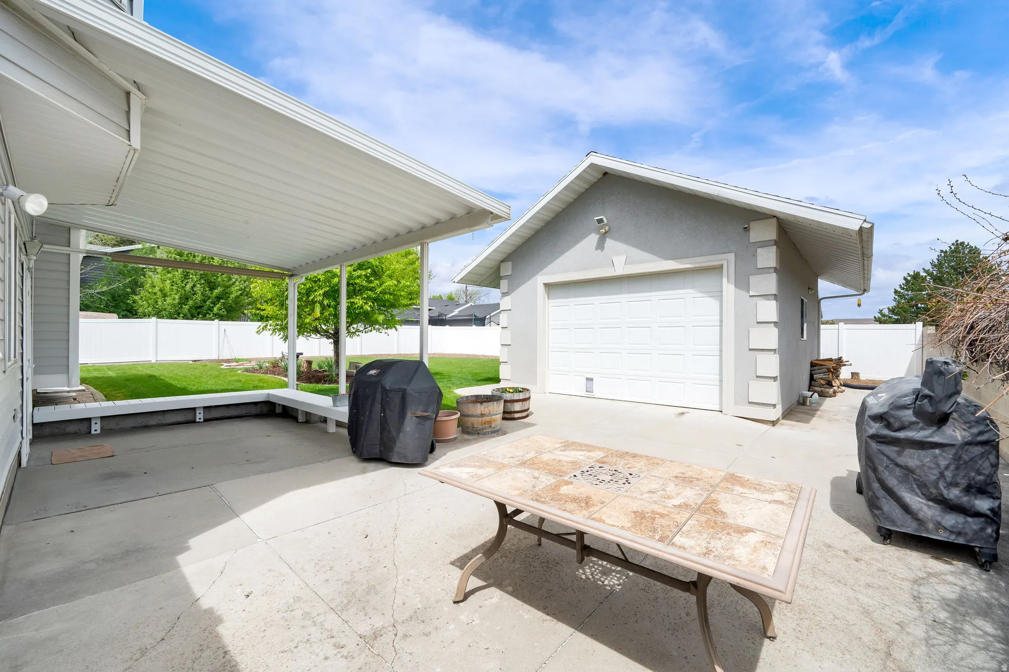 Fenced backyard featuring an outdoor structure, a grill, a garage, and a patio area