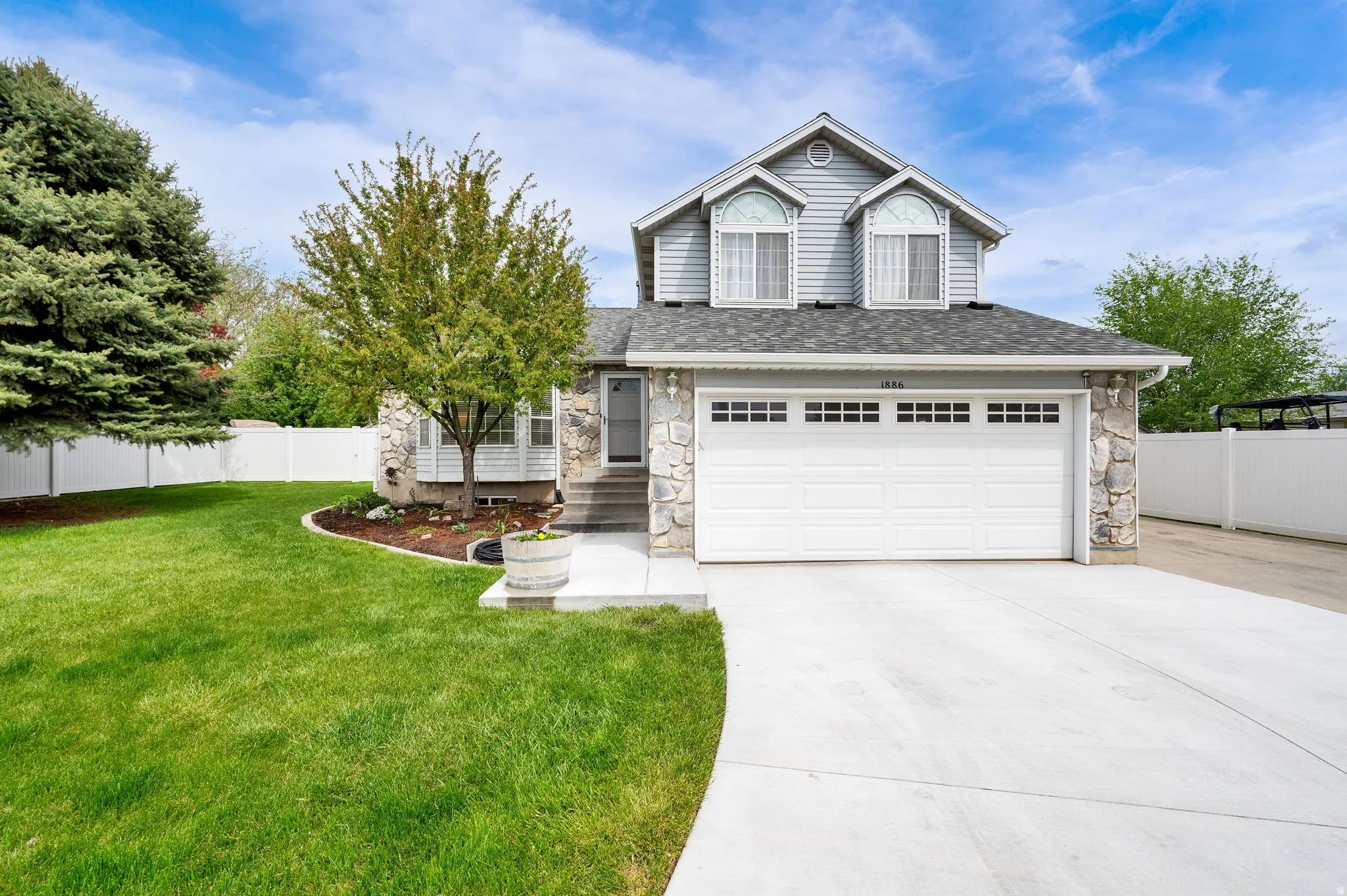 View of front of home with stone siding, concrete driveway, an attached garage, and roof with shingles