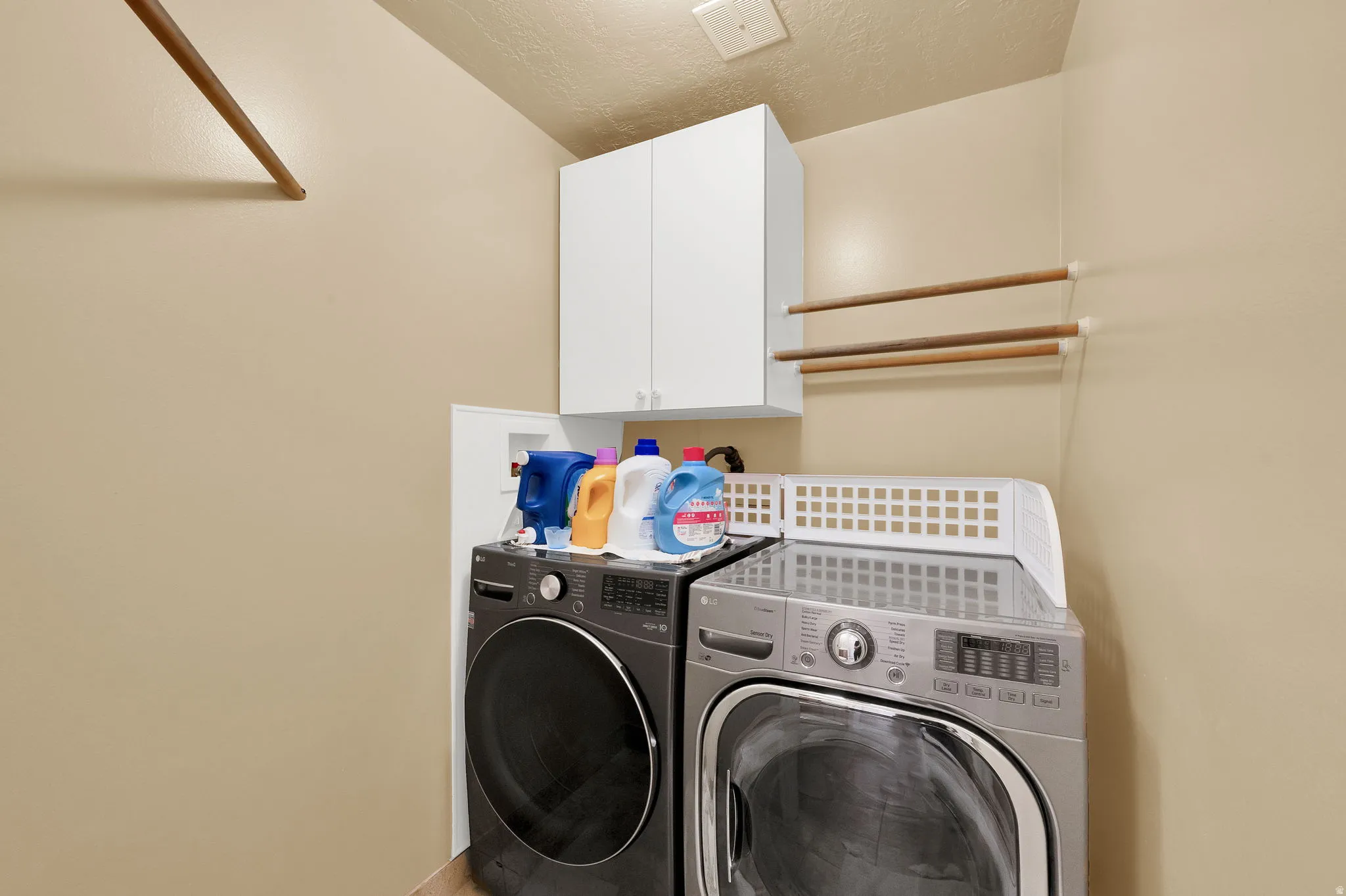 Laundry area with washing machine and dryer, cabinet space, and a textured ceiling