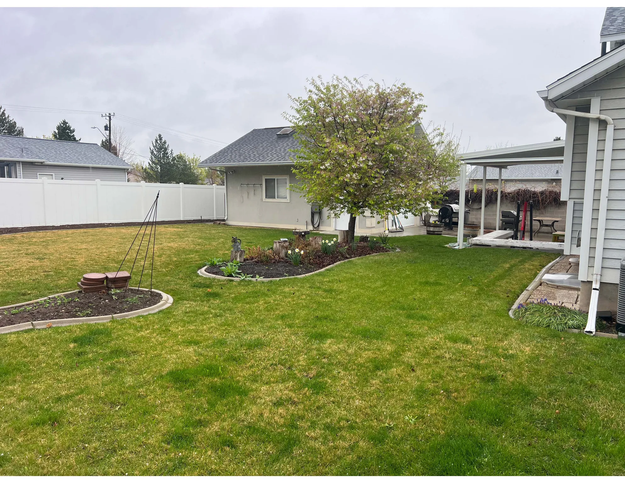 Fenced backyard with a patio area and second garage.